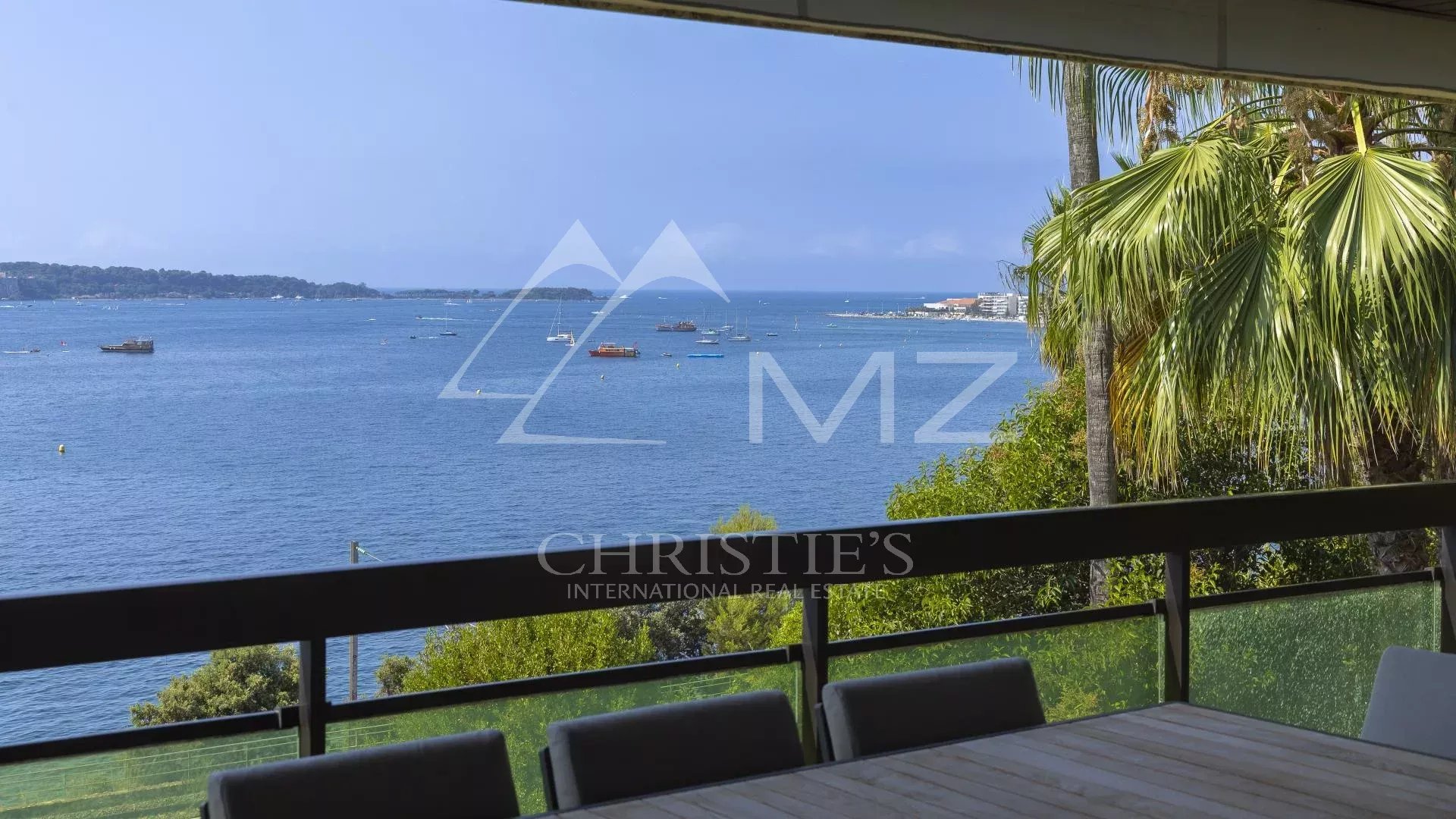 Vue panoramique sur la Méditerranée depuis un appartement à Cannes, avec terrasse et mobilier extérieur.