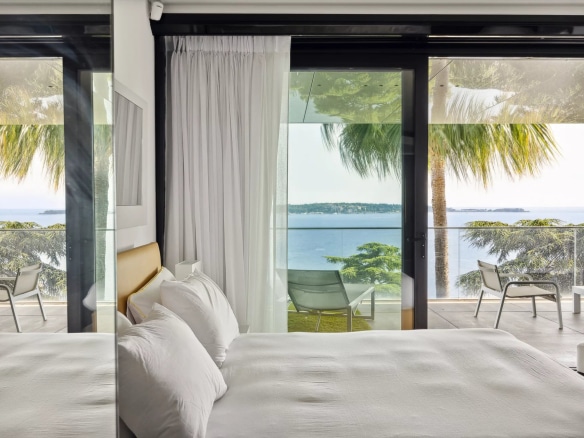 Chambre d'un appartement de luxe avec vue sur la mer à Cannes, terrasse et palmiers visibles.
