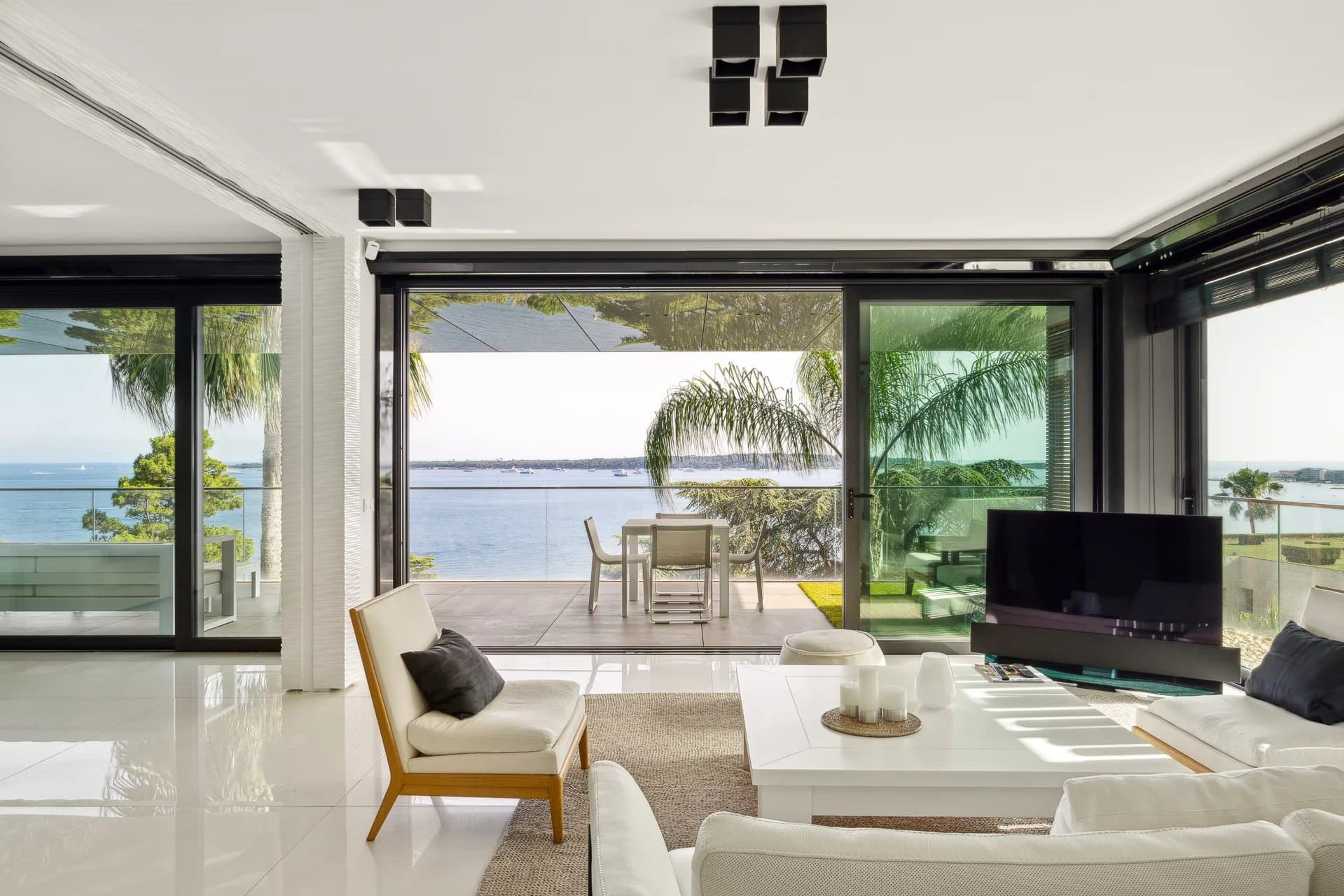 Intérieur d'un appartement moderne avec vue sur la mer à Cannes, terrasse spacieuse et mobilier contemporain.