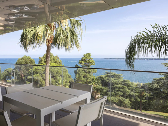 Terrasse d'un appartement de luxe avec vue sur la mer à Cannes, entourée de palmiers.