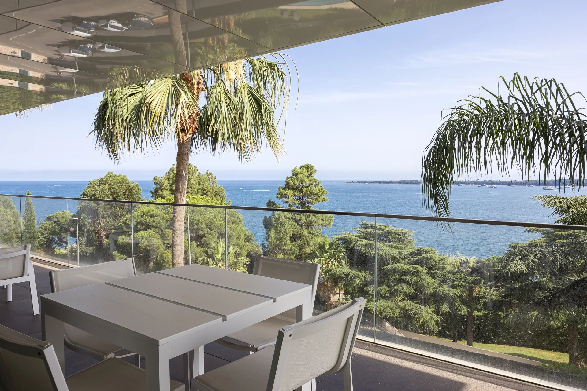 Terrasse d'un appartement de luxe avec vue sur la mer à Cannes, entourée de palmiers.