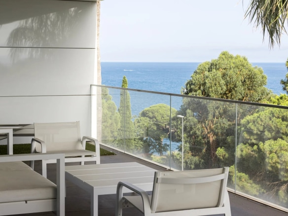 Terrasse d'un appartement de luxe à Cannes avec vue sur la mer et des chaises blanches.