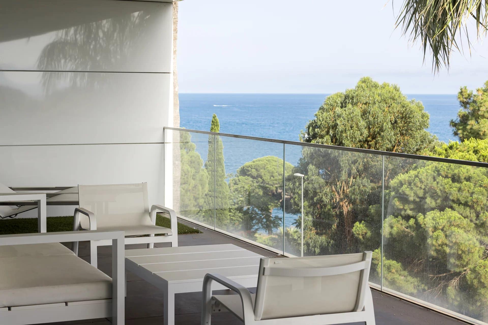 Terrasse d'un appartement de luxe à Cannes avec vue sur la mer et des chaises blanches.