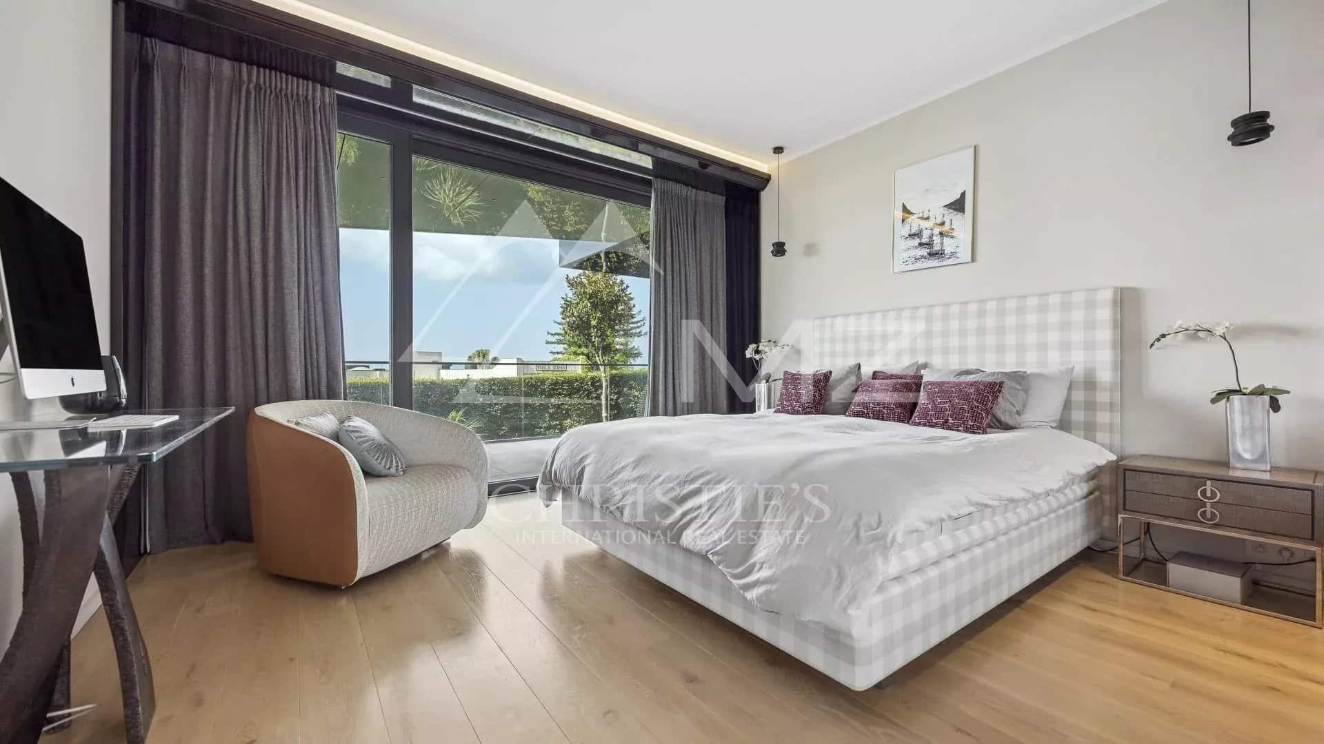 Room in a contemporary apartment with bed, desk and view of the outside in Cannes.
