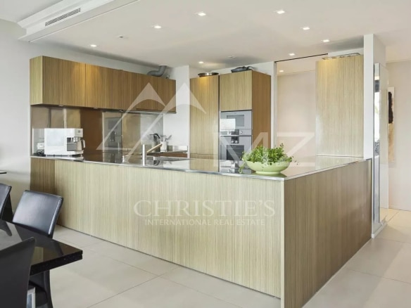 Modern and sleek kitchen in a contemporary apartment in Cannes, with central island and wooden furniture.