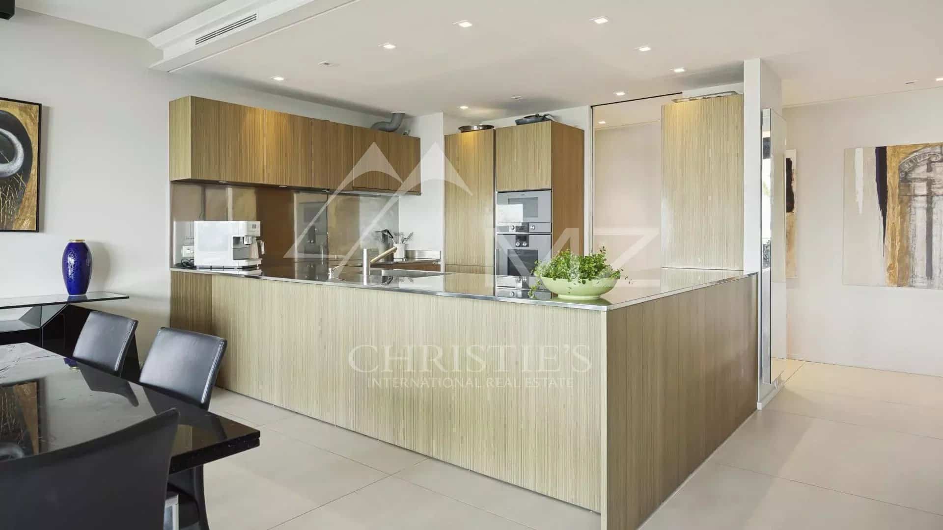 Modern and sleek kitchen in a contemporary apartment in Cannes, with central island and wooden furniture.