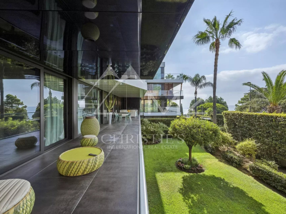 Terrace of a contemporary apartment overlooking a garden and palm trees in Cannes, California.