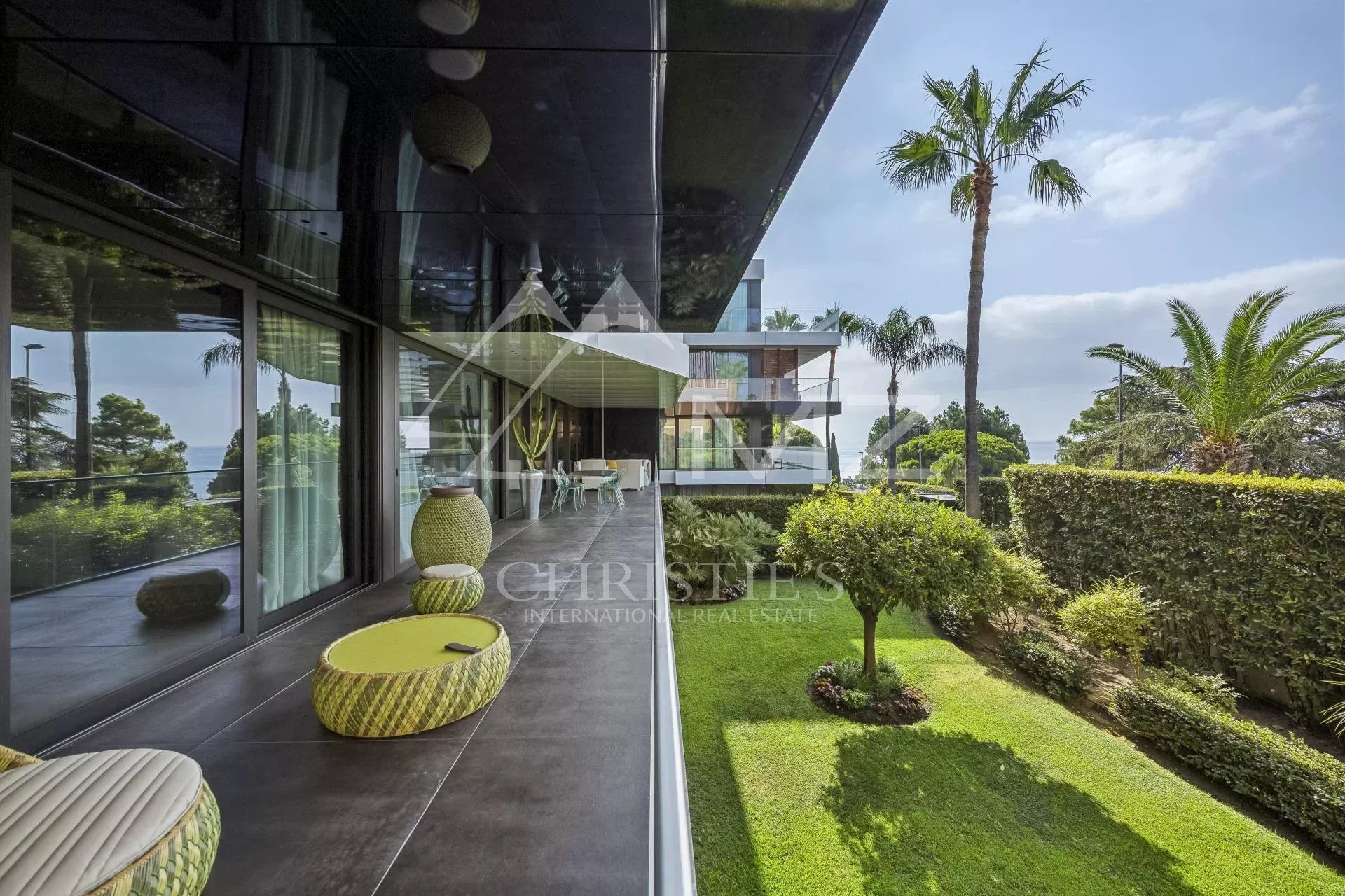 Terrace of a contemporary apartment overlooking a garden and palm trees in Cannes, California.