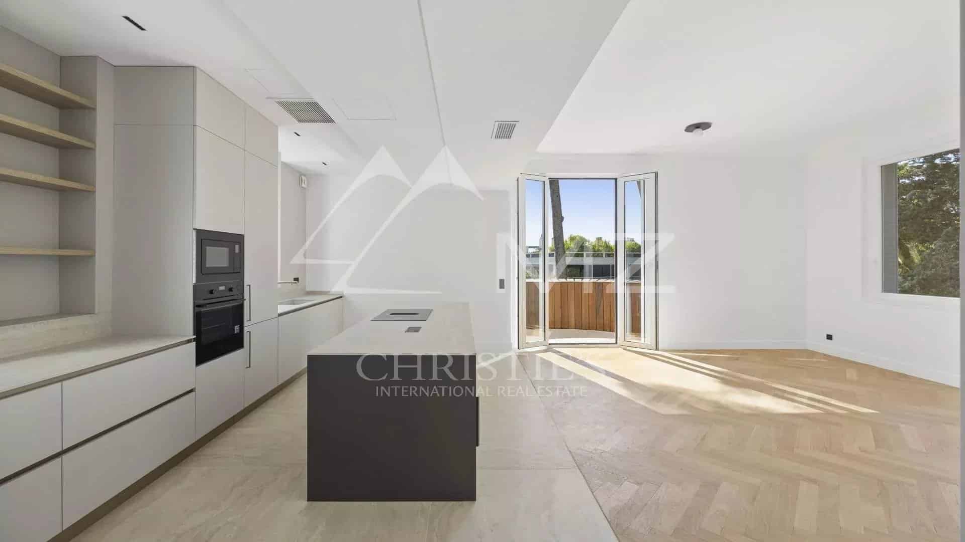 Cuisine moderne d'un appartement rénové à Le Cannet, avec îlot central et grandes fenêtres.