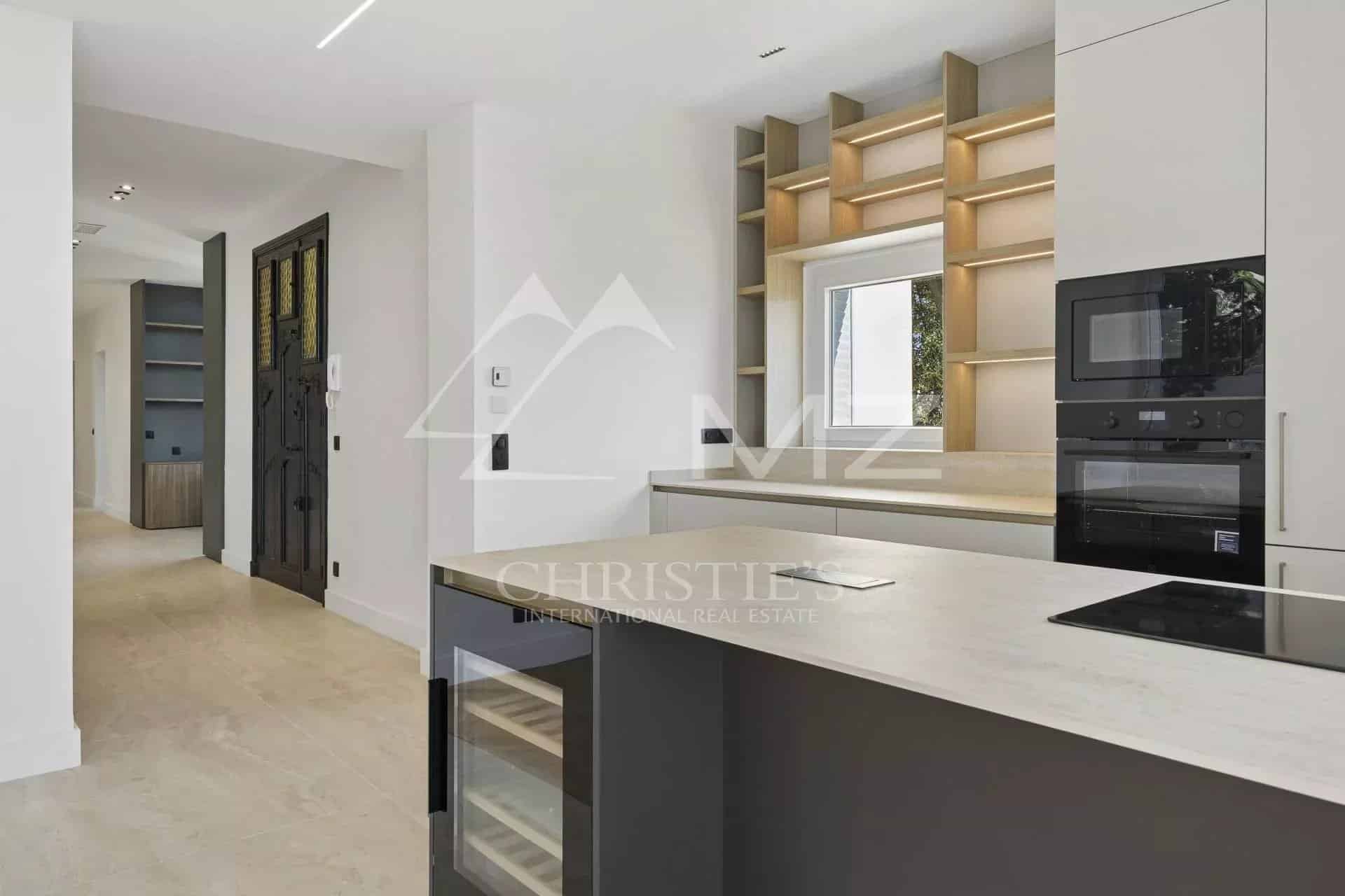 Cuisine moderne d'un appartement rénové à Le Cannet, avec des meubles clairs et un plan de travail en pierre.