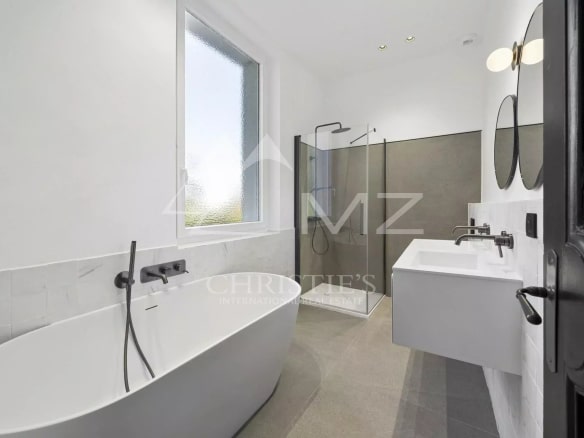 Salle de bain moderne avec baignoire, douche et double vasque dans un appartement rénové.