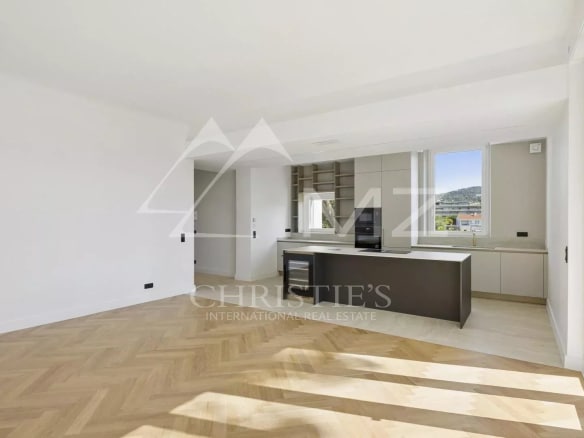 Intérieur d'un appartement rénové à Le Cannet avec cuisine ouverte et parquet en bois.