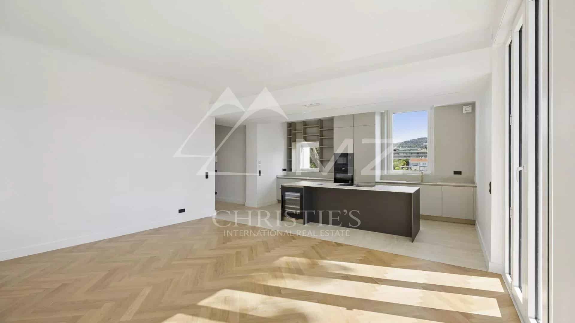Intérieur d'un appartement rénové à Le Cannet avec cuisine ouverte et parquet en bois.