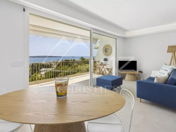 Intérieur d'un appartement rénové à Cannes avec vue mer, salon lumineux et terrasse.