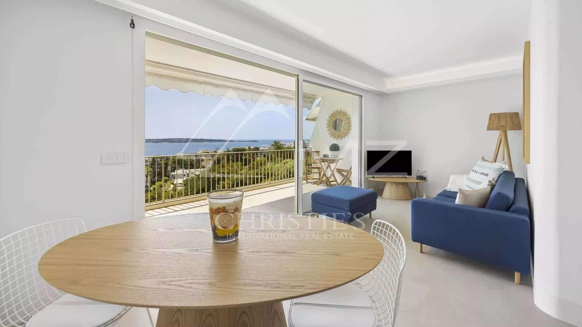 Intérieur d'un appartement rénové à Cannes avec vue mer, salon lumineux et terrasse.
