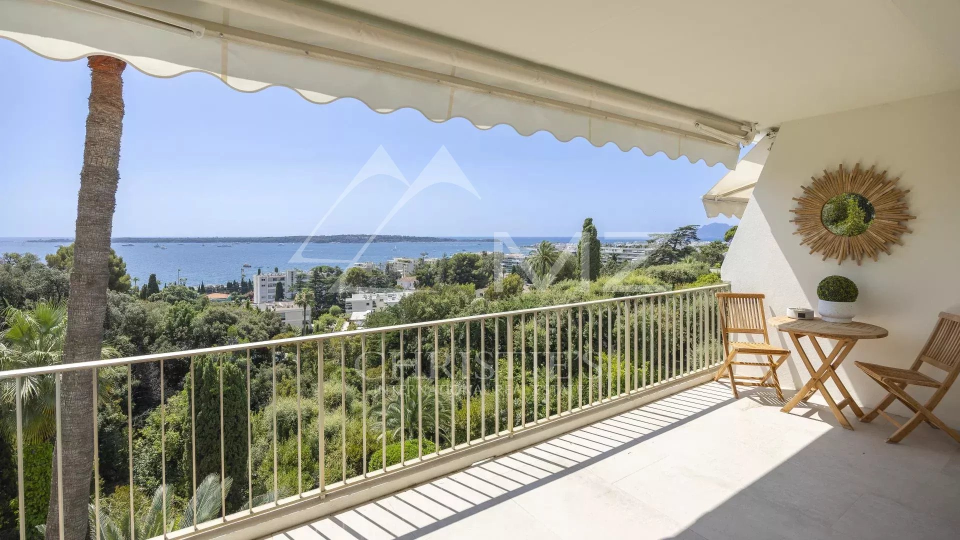 Terrasse d'un appartement à Cannes avec vue panoramique sur la mer et le parc environnant.