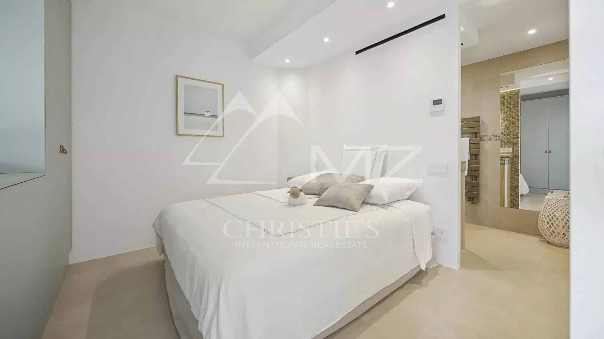 Chambre d'un appartement rénové à Cannes, avec lit double et décoration moderne.