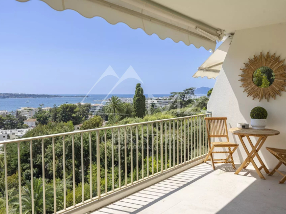 Terrasse d'un appartement avec vue panoramique sur la mer à Cannes, entourée de verdure.