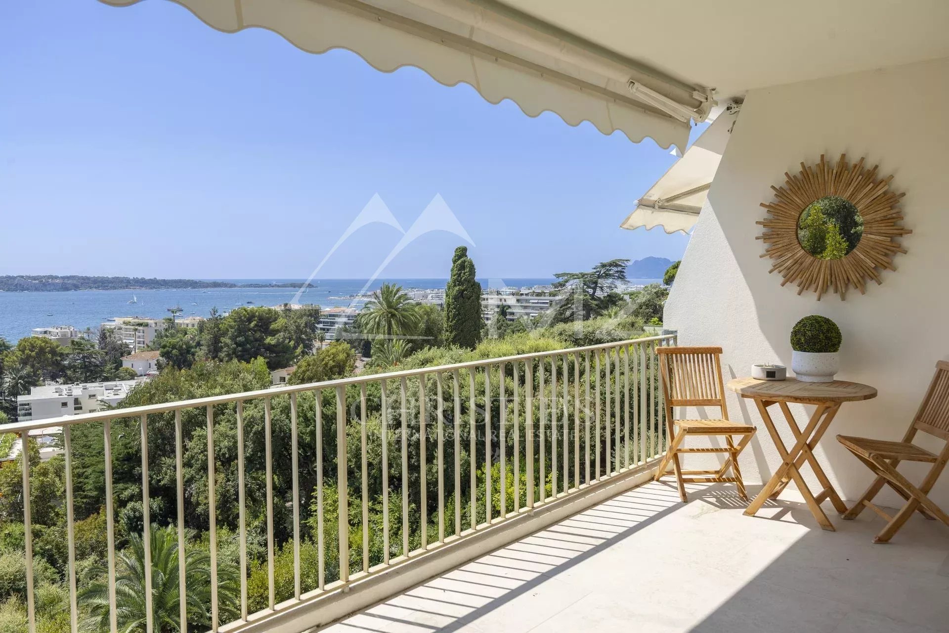 Terrasse d'un appartement avec vue panoramique sur la mer à Cannes, entourée de verdure.