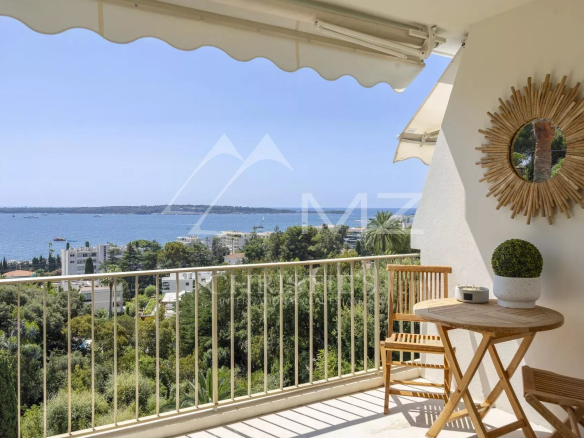 Terrasse d'un appartement avec vue panoramique sur la mer à Cannes, mobilier en bois et décoration moderne.