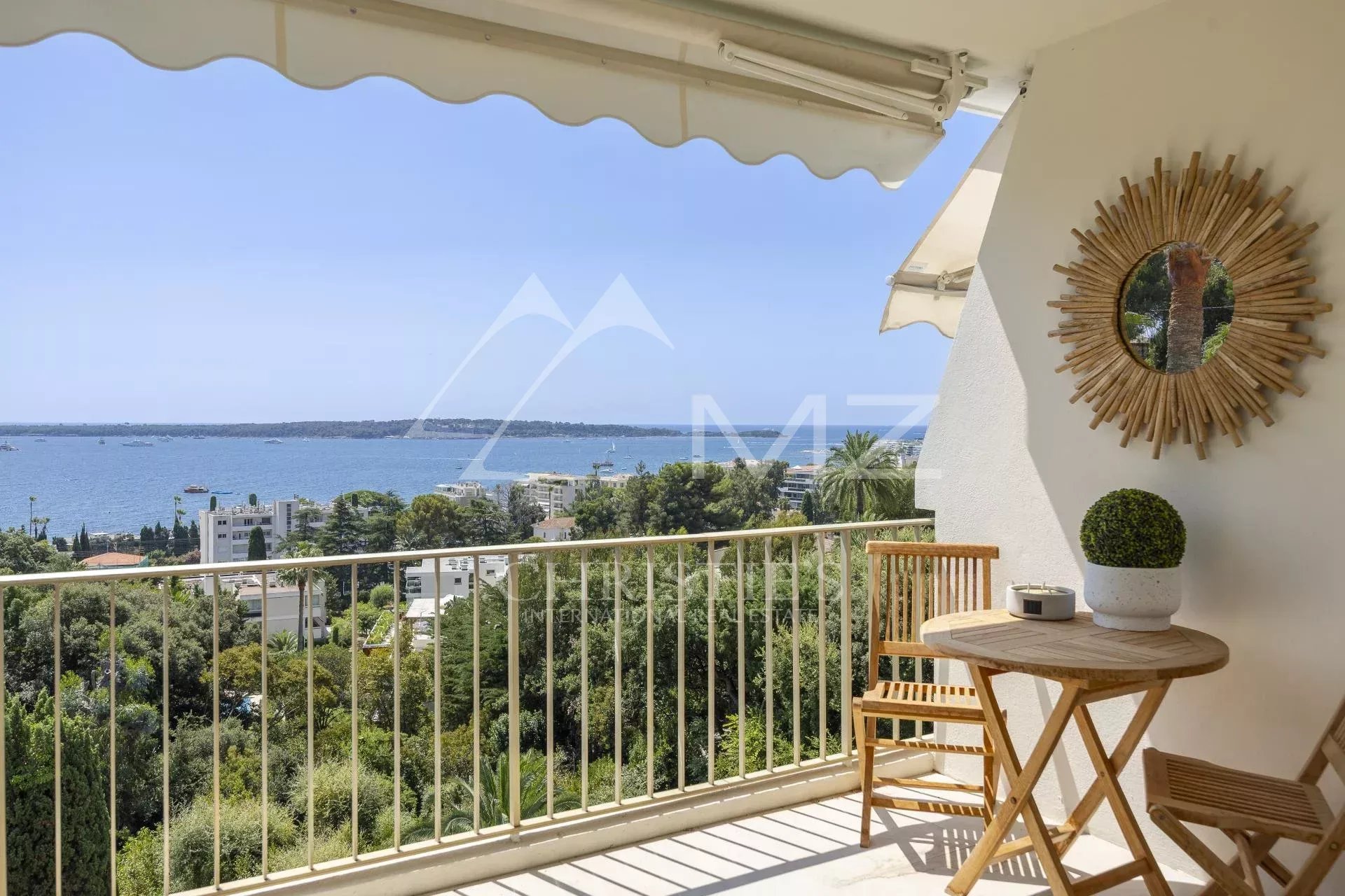 Terrasse d'un appartement avec vue panoramique sur la mer à Cannes, mobilier en bois et décoration moderne.