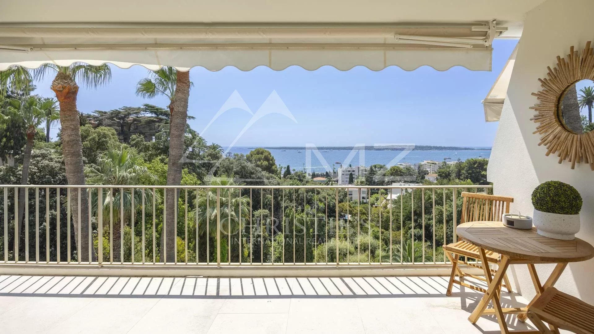 Terrasse d'un appartement à Cannes avec vue panoramique sur la mer et le parc environnant.