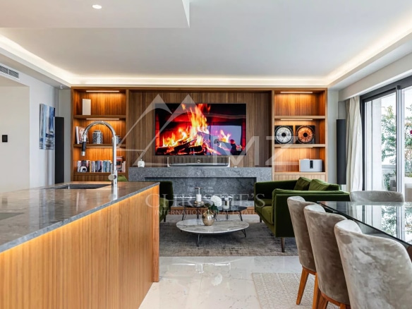 Interior of a modern penthouse with open kitchen, bright living room and fireplace, in Cannes.