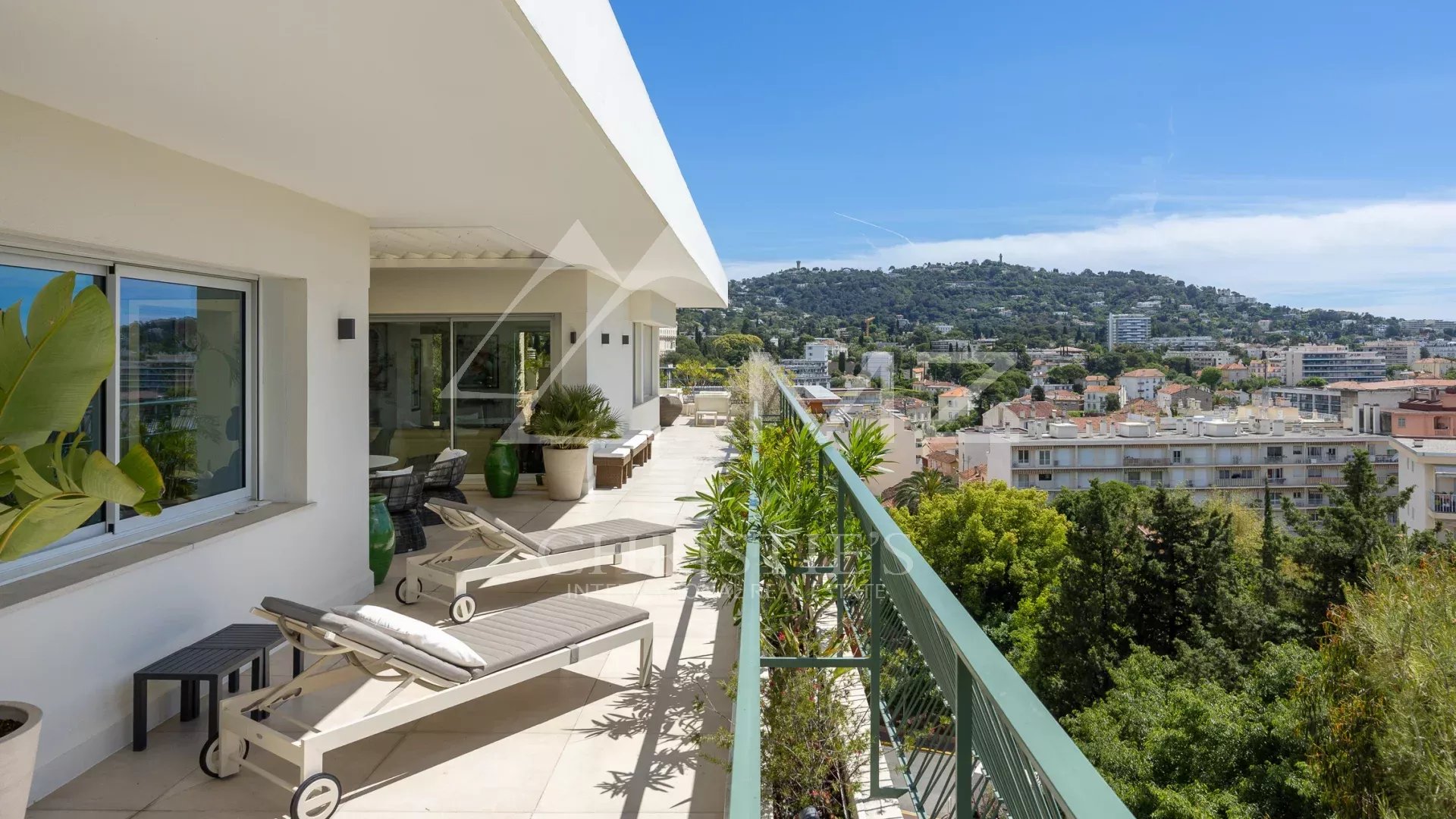 Rooftop terrace of a villa in Cannes with views of the hills and the sea.
