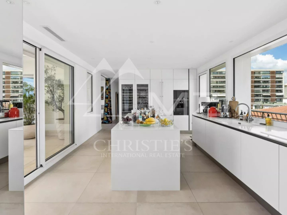 Modern kitchen in a rooftop villa in Cannes, with large windows offering views of the city.