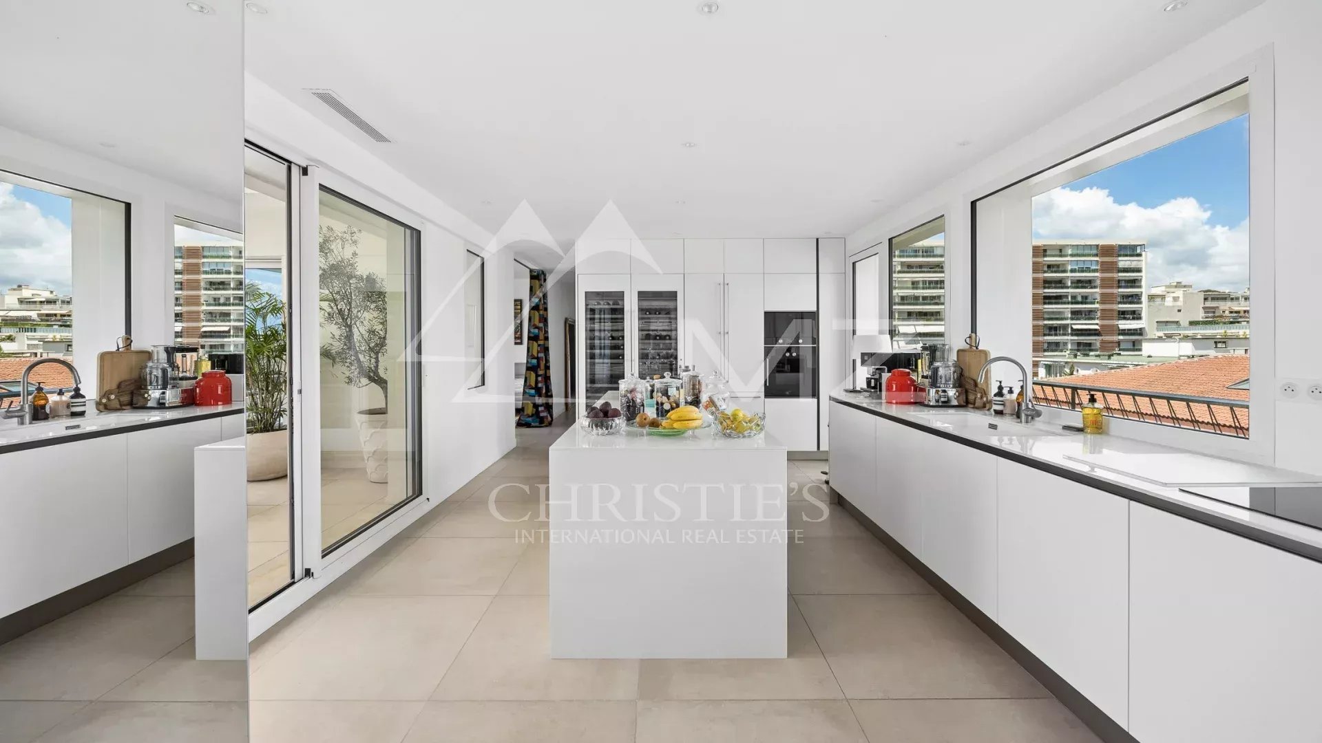 Modern kitchen in a rooftop villa in Cannes, with large windows offering views of the city.