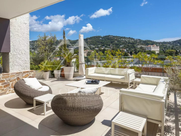 Spacious terrace of a villa in Cannes with views of the hills and the blue sky.