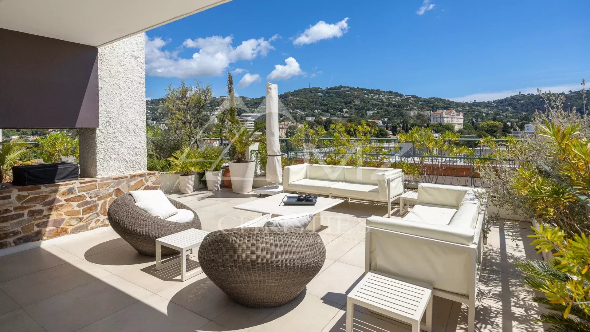 Spacious terrace of a villa in Cannes with views of the hills and the blue sky.