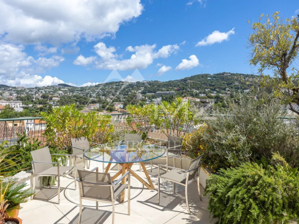Terrace of a villa in Cannes with views of the hills and blue sky.