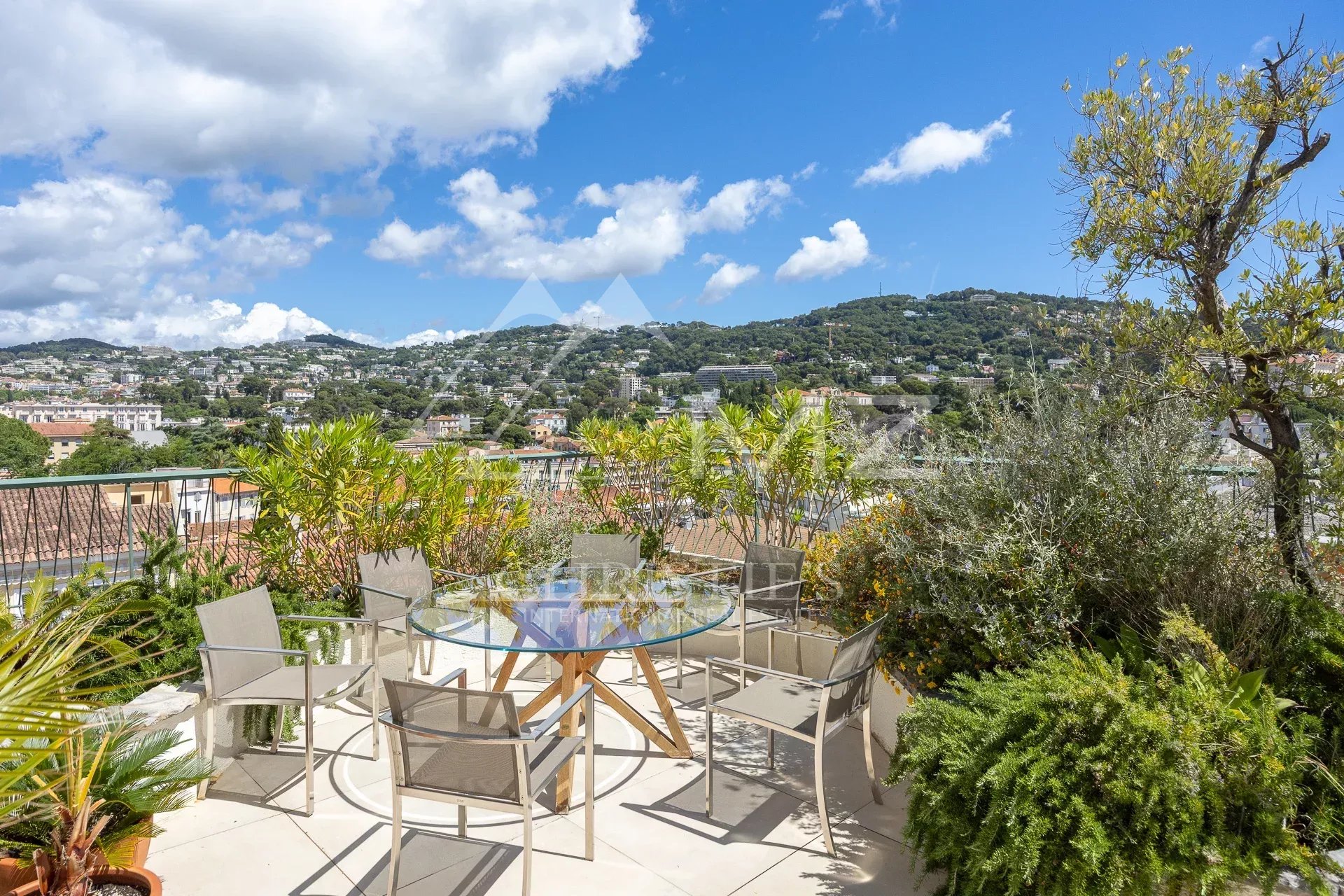 Terrace of a villa in Cannes with views of the hills and blue sky.