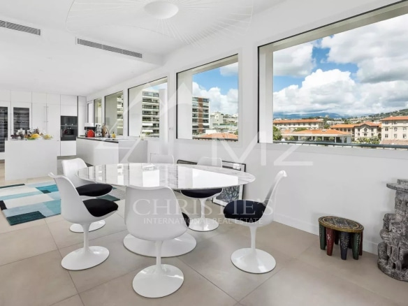 Interior of a rooftop villa in Cannes with a modern dining room and large windows offering a view.