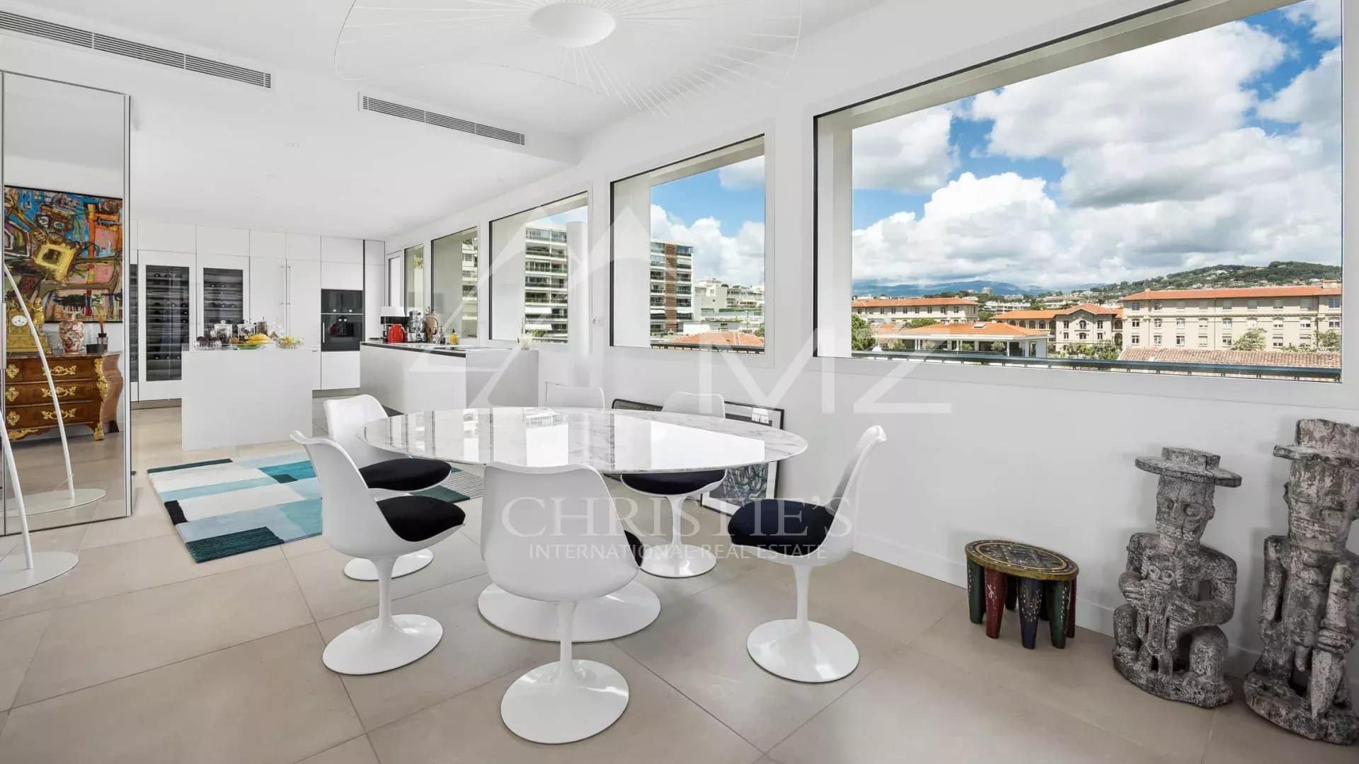 Interior of a rooftop villa in Cannes with a modern dining room and large windows offering a view.