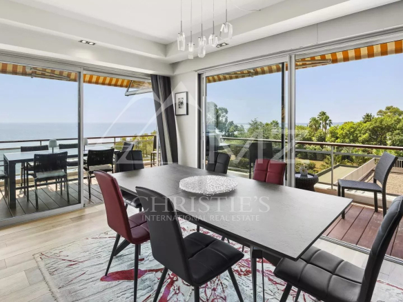 Modern dining room with sea view, open windows, contemporary furniture.