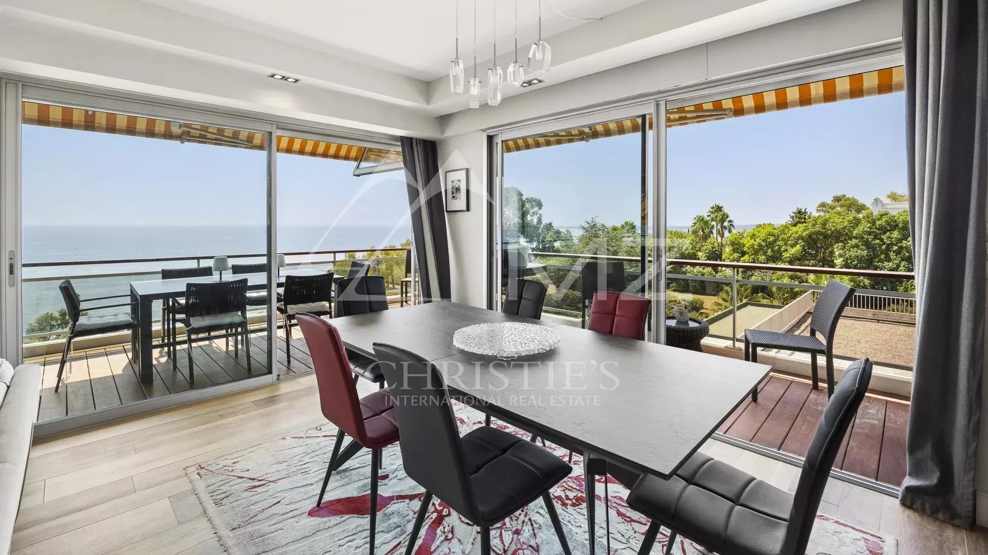 Modern dining room with sea view, open windows, contemporary furniture.