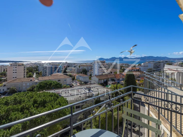 Vue mer depuis le balcon d'un appartement au dernier étage à Cannes, avec des bâtiments environnants.