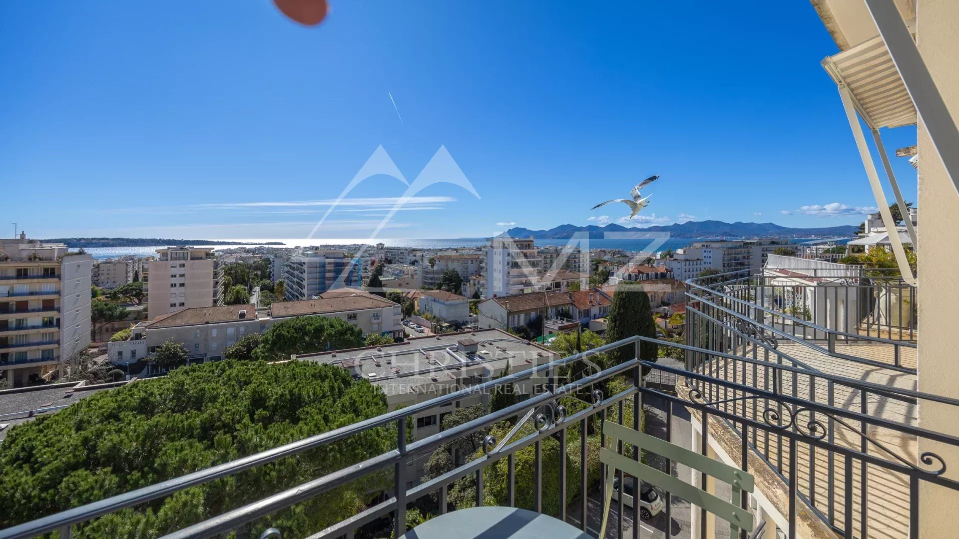 Vue mer depuis un appartement à Cannes Vue mer depuis le balcon d'un appartement au dernier étage à Cannes, avec des bâtiments environnants.