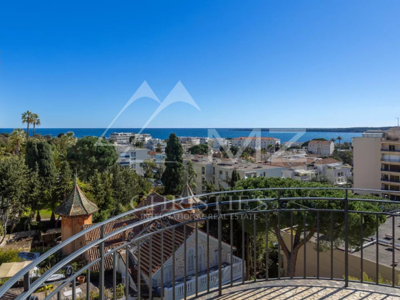 Vue mer depuis le dernier étage d'un appartement à Cannes, entouré de verdure.
