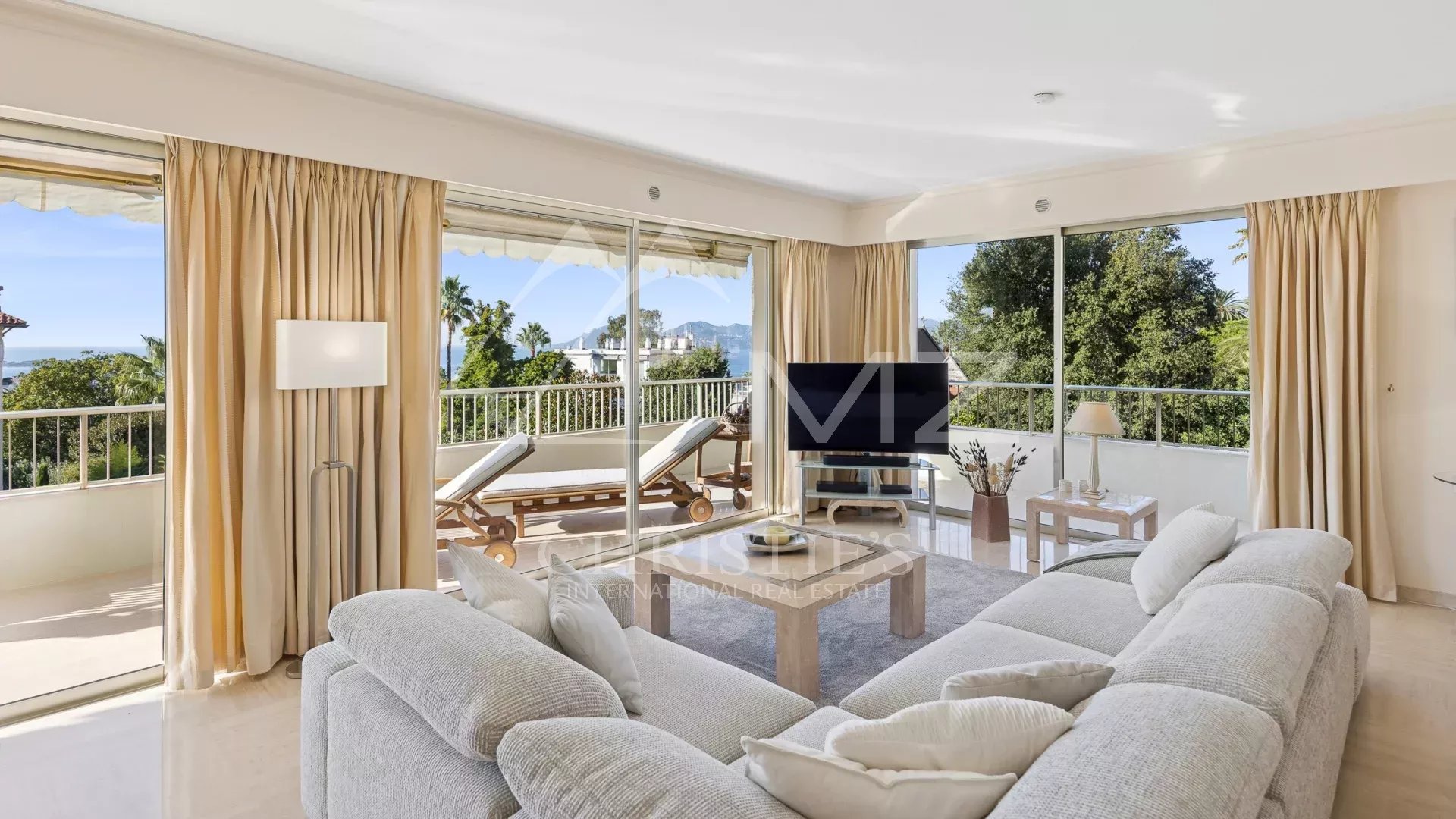 Salon lumineux d'un appartement d'angle à Cannes avec vue sur la mer et terrasse.