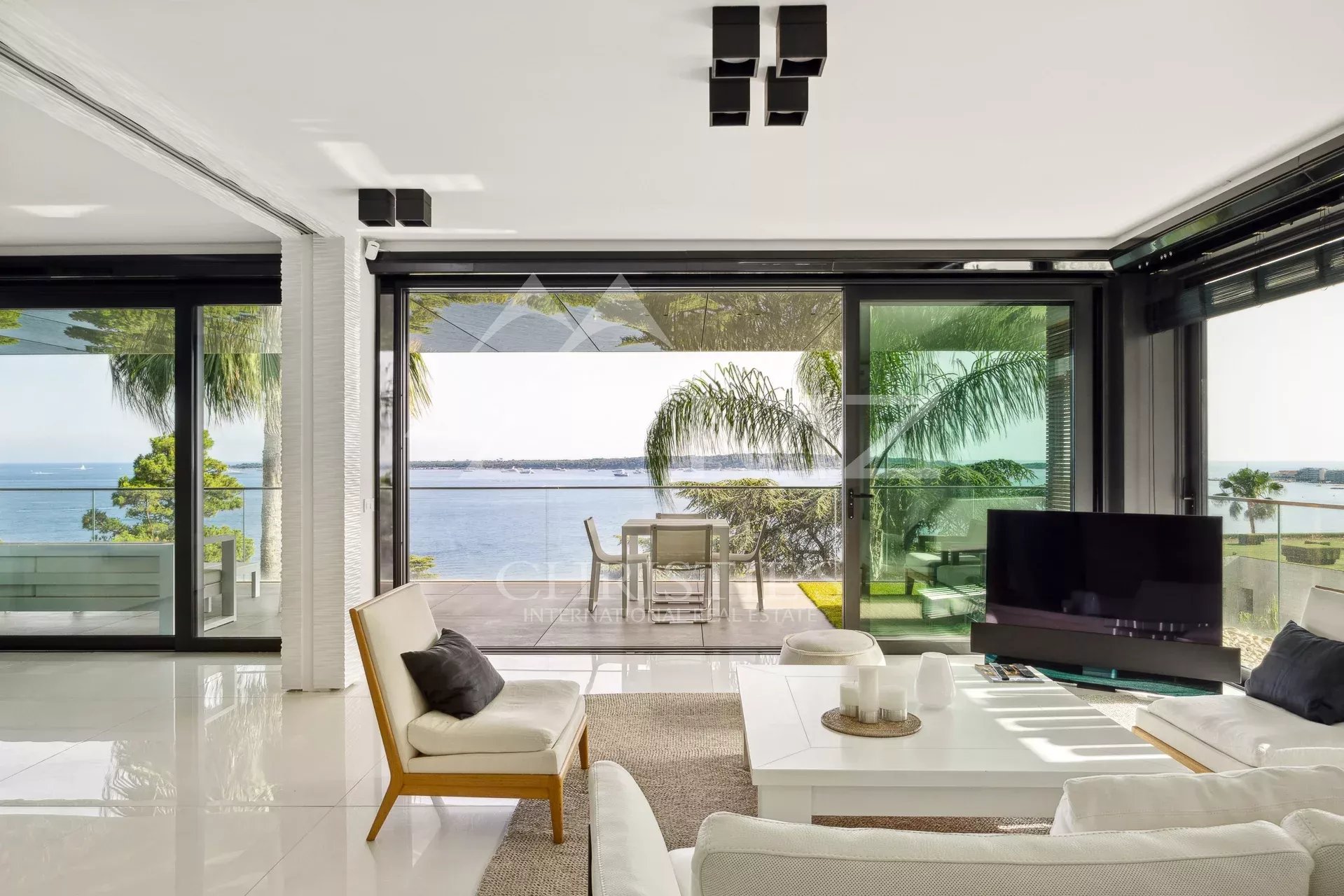 Intérieur d'un appartement de luxe avec vue sur la mer à Cannes, fenêtres ouvertes sur la terrasse.
