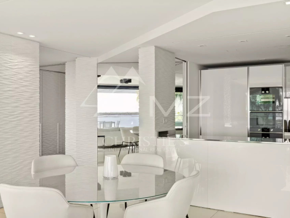 Intérieur d'un appartement moderne avec cuisine ouverte et salle à manger, vue sur la mer.