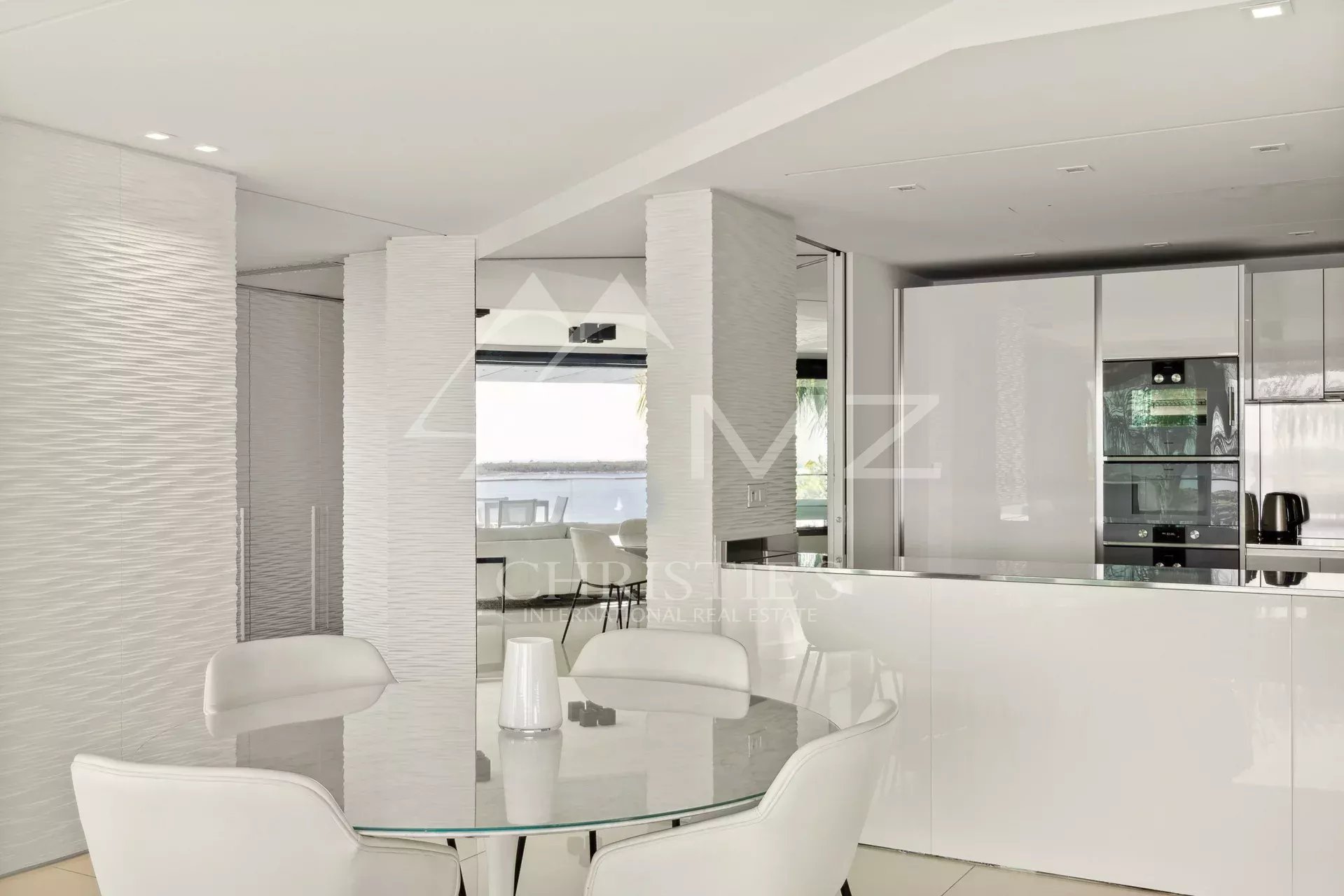Intérieur d'un appartement moderne avec cuisine ouverte et salle à manger, vue sur la mer.