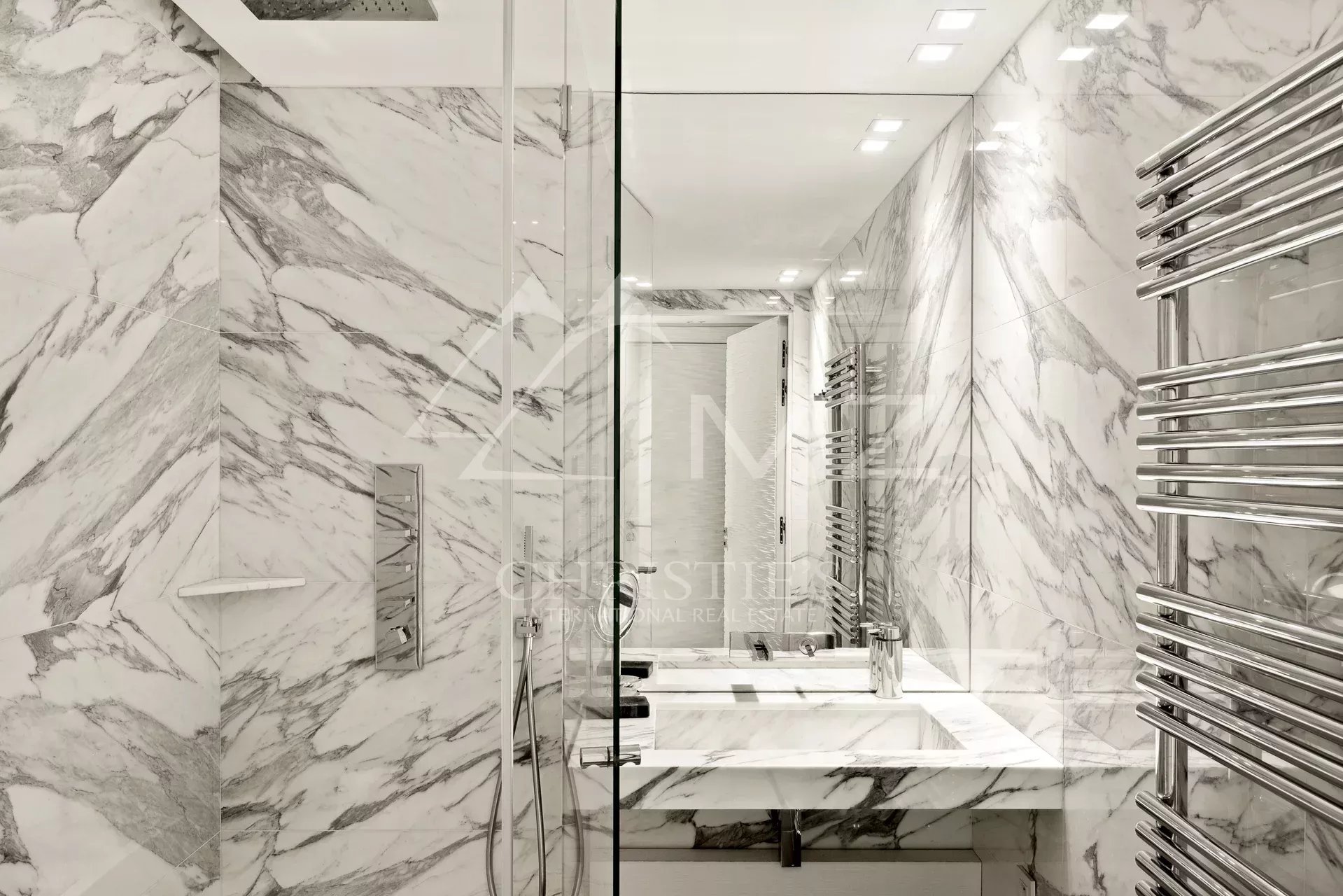 Salle de bain moderne avec murs en marbre et douche en verre
