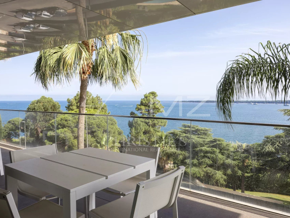 Terrasse d'un appartement de luxe avec vue sur la mer à Cannes, entourée de palmiers.