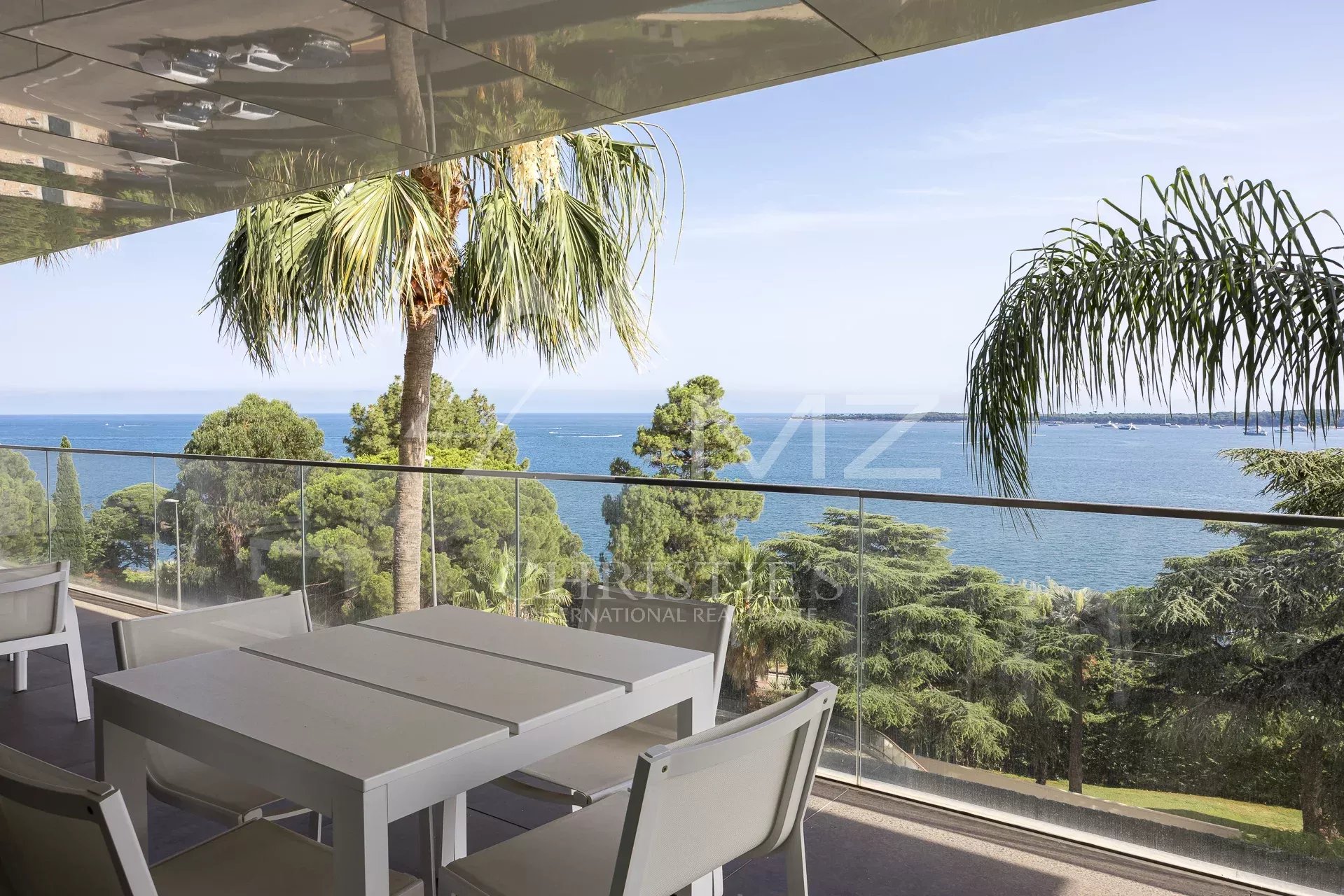 Terrasse d'un appartement de luxe avec vue sur la mer à Cannes, entourée de palmiers.