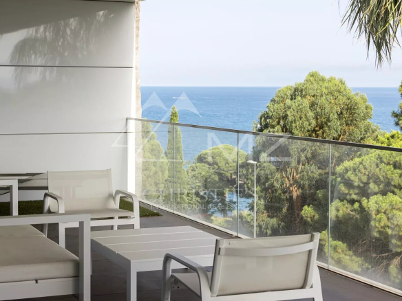 Terrasse d'un appartement avec vue sur la mer à Cannes, entourée d'arbres.