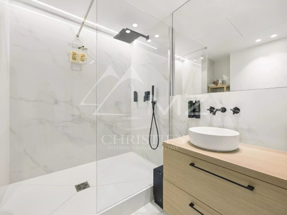 Modern bathroom with glass shower and wooden vanity.